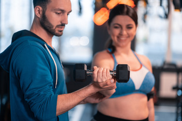 Fototapeta na wymiar Handsome trainer teaching obese woman using barbells