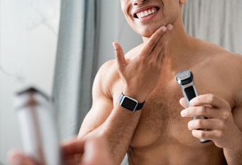 Happy muscular naked man with electric razor