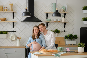 Pregnant couple in love sitting in the kitchen