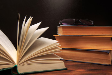 Open book with glasses on books background.