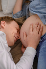 The future father listens as his child beats in the belly of his pregnant wife.