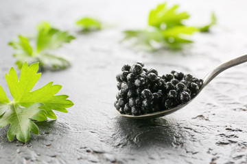 Fototapeta na wymiar Spoon with delicious black caviar on dark background