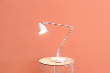 Beautiful stylish lamp on table against color background