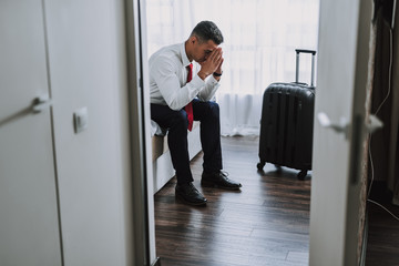 Sad elegant man is waiting in hotel room
