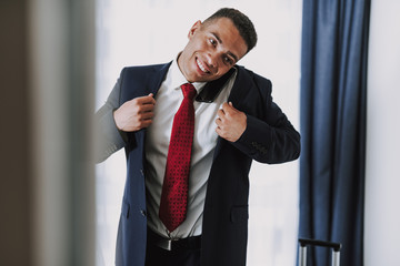 Happy executive in suit is talking on phone indoors