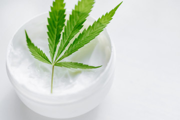 Green cannabis leaf on a jar of cream. Marijuana and hemp paste jar isolated on white. Natural cosmetics with the content of CBD