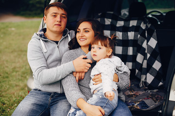 Family sitting on a trunk. Mother in a gray sweater. Cute little girl with a father