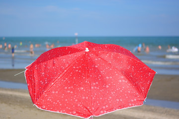 a nice red beach umbrella in front of the blue sea