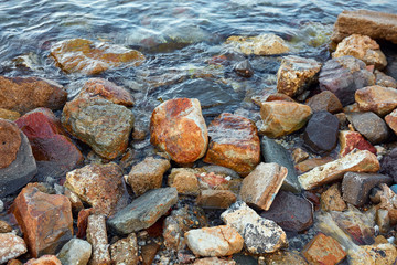 Big colorful riverbed stones near the water