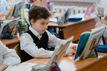The young schoolboy focused looking at the book in the classroom