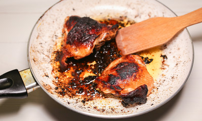 Fried chicken in oil. Unhealthy food. Burnt pan. Damaged kitchenware. Leftovers.
