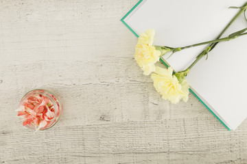 Top view flowers and book on wooden background