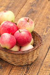 Red apples in wicker basket on wooden boards