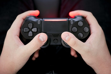 Hands of a gamer kid holding a black gamepad © Cagkan
