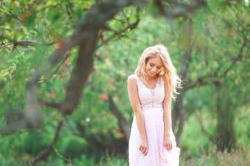 Naklejka premium beautiful young woman in a gentle pink dress on nature
