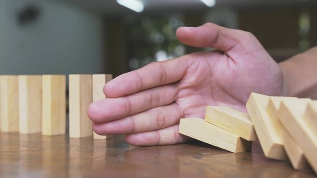 Businessman hand stop dominoes continuous toppled or risk.