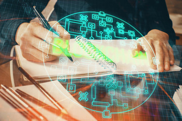Cryptocurrency hologram over woman's hands writing background. Concept of blockchain. Multi exposure