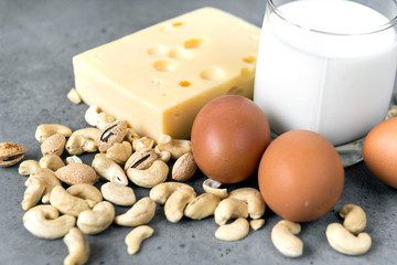 eggs, cheese, nuts, glass of milk on grey background