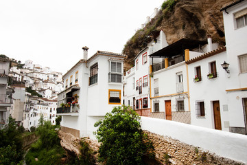Fototapeta na wymiar Narrow street along the river Setenil de las Bodegas with houses under the overhanging cliffs, Spain, Andalusia