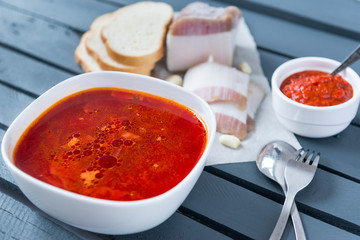 soup, a plate of red Ukrainian borscht with bacon and ketchup on a gray wooden background