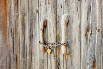 Old wooden door locked with rusty chain and padlock