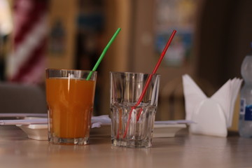 two glasses on the table. one empty, one with juice. catering
