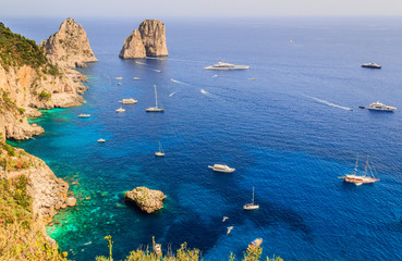Panoramic view of famous Faraglioni Rocks, most visited travel attraction of Capri Island, Italy. Beautiful paradise landscape with azure sea in summer sunny day.