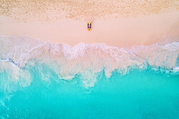 Luftaufnahme einer Frau am Strand in einem Bikini liegend und sonnenbadend