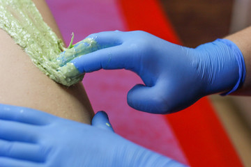 Girl cosmetician in medical gloves with pasta for shugaring