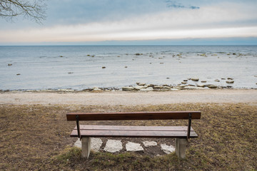 Lonely wooden bench on the autumn sea with cloudy sky