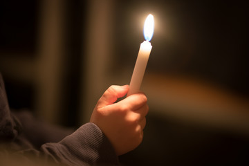 burning church candles in the hands of children on a dark background