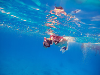 Snorkeling Girl with an action camera floats in the sea and shoots a video camera