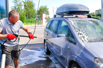 Man pours active foam car body. Car wash. Self-service washing complex. High pressure car wash.