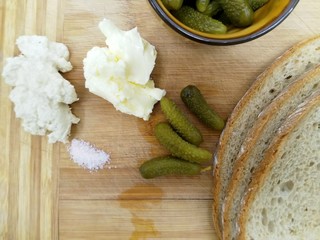 korniszony z masłem chrzanem i chlebem na desce drewnianej