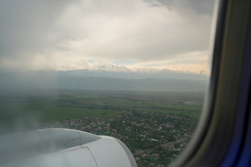Fototapeta na wymiar Airplane window outside view and cloudy ice mountain landscape Shymkent Kazakhstan.