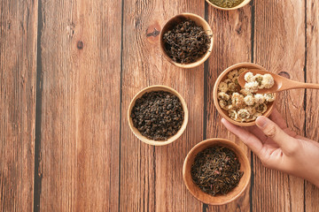assortment of dry tea in white bowls on wooden surface