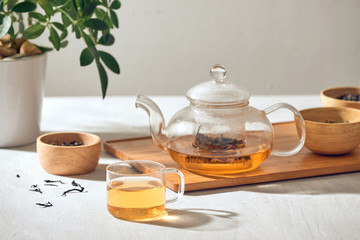 Tea in a transparent cup and teapot on a wooden background