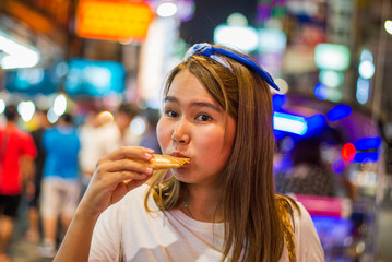 Asian young woman travel in China town at Thailand at Night,Woman travel and eating Night street food market at Yaowarat road, China town Bangkok, Thailand 