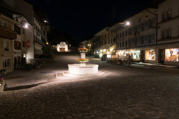 the historic medieval village of Gruyeres with the village square fountain at night