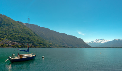 Fototapeta na wymiar sailboat on the shores of Lake Geneva with great view of the Swiss Alps behind as seen from the Montreux Riviera
