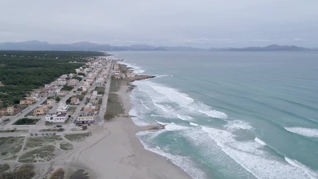 Aerial views of San Serra de Marina town, roads and amenities. Mallorca, Balearic Islands, Spain. Aerial slow anti-clockwise. River Borges, sand dunes, nature reserve, sea and mountain views.