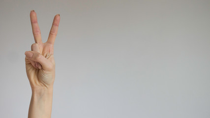 Female hand with two fingers up in peace or victory symbol.