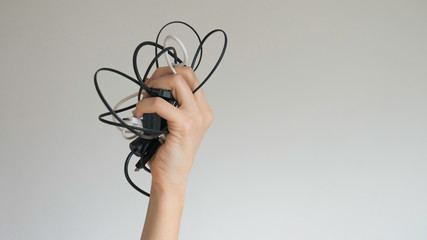 Black and white cables in a woman's hand on a light gray background