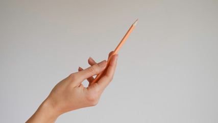 Isolated  woman's hand holding a wooden color pencil 