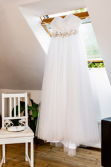 beautiful wedding white dress and shoes hanging in the bedroom waiting for the bride