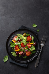 Fresh vegetable salad with tomato, cucumber, bel pepper and olives salad on black plate