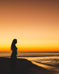 silhouette of woman on the beach at sunset - 274217121