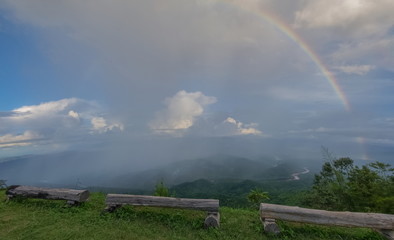 view of raining on top hill with rainbow in the sky background, evening at Doi Samur Dao, Sri Nan National Park, Nan, northern of Thailand.