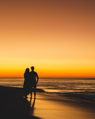 silhouette of man and women on the beach at sunset - 274217574