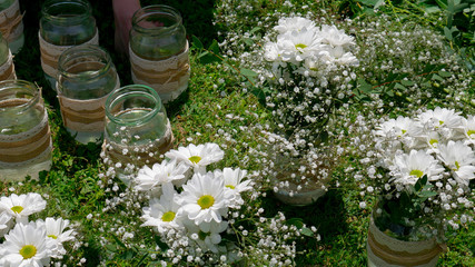Empty and full jars with white daisy bouquets - outside on the green grass